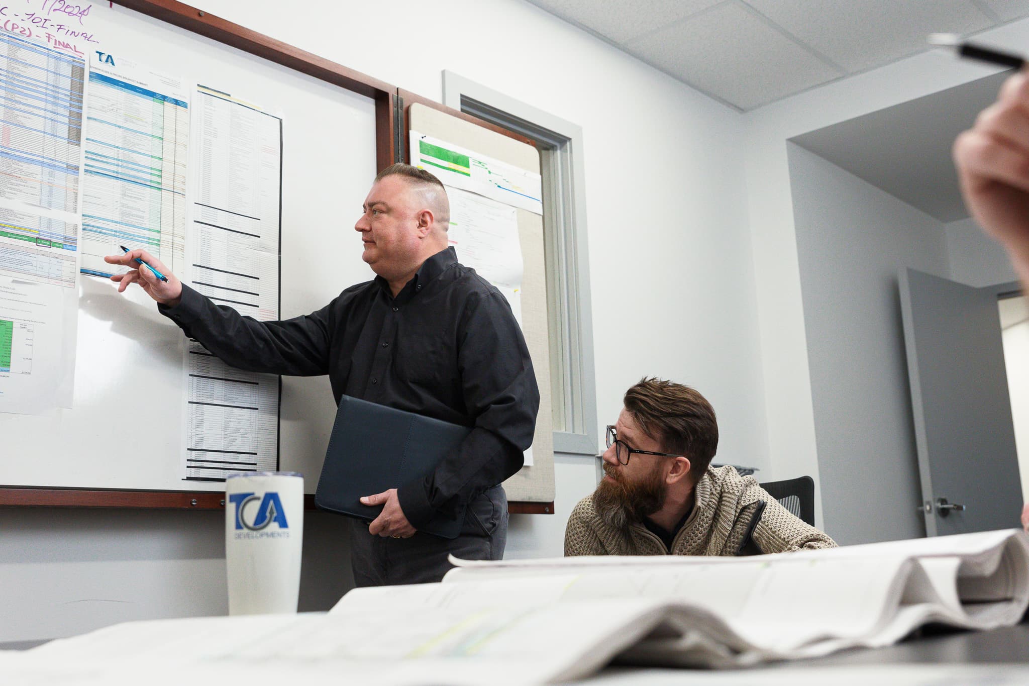 TCA team reviewing a project schedule on a whiteboard