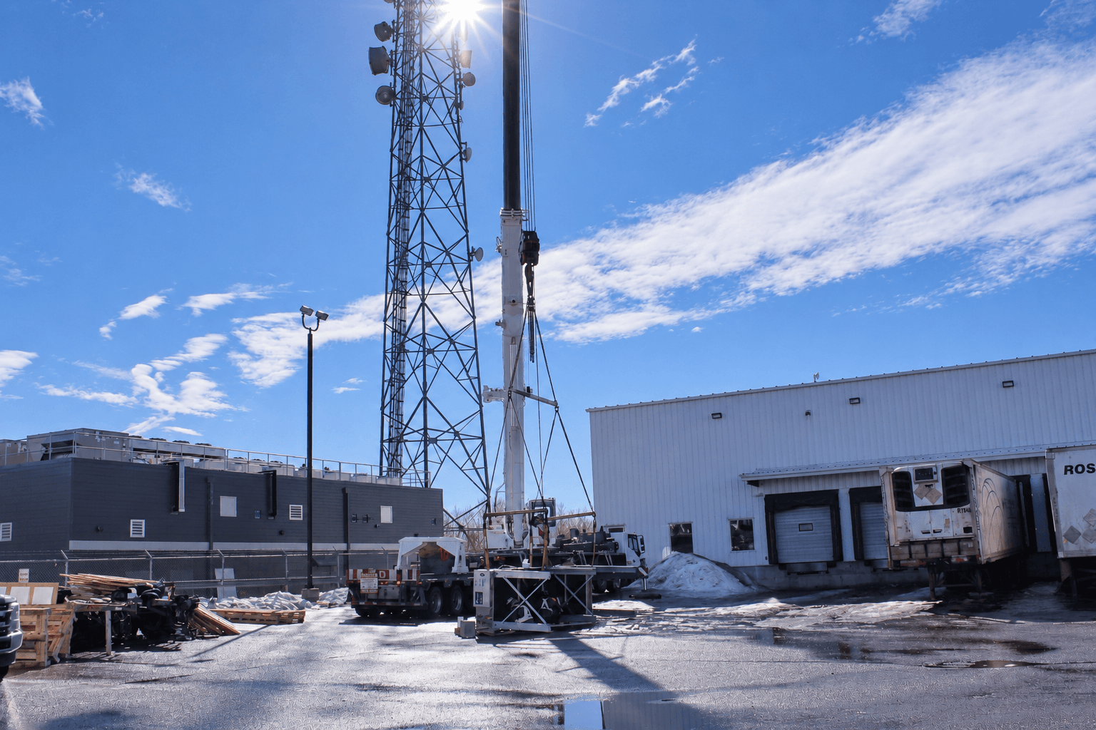 Crane beside a communications tower with equipment at its base